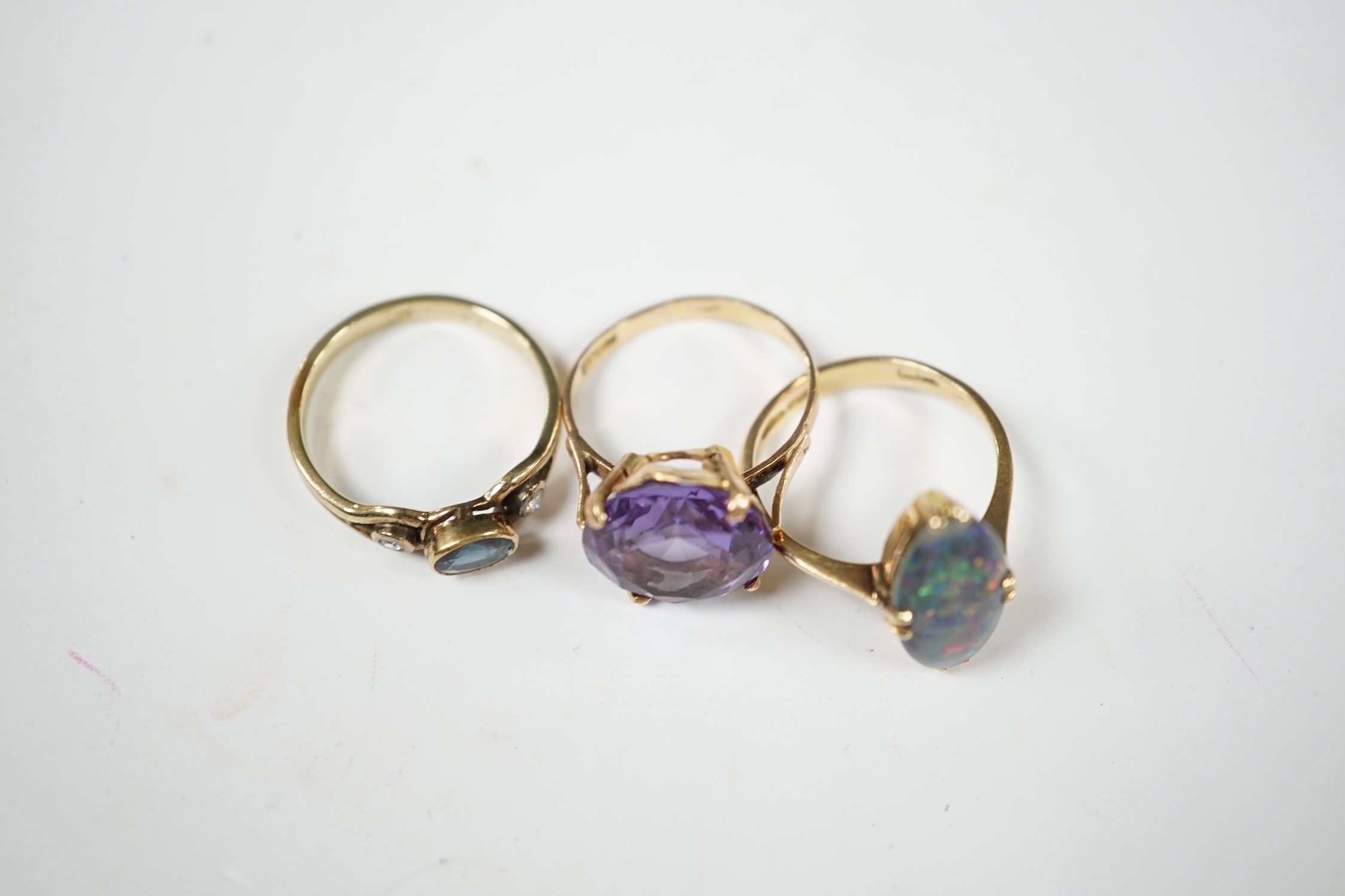 A 14k and black opal double set oval ring, size N, a yellow metal, sapphire and diamond set three stone ring and a Middle Eastern yellow metal and synthetic colour change corundum set ring, gross weight 8.9 grams. Condit